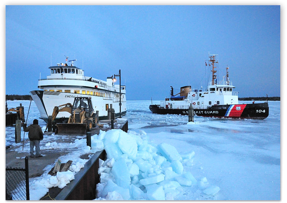 Backhoes clear the ice from the Emerald Isle's berth as the Biscayne Bay looks on having cleared the channel into the harbor
